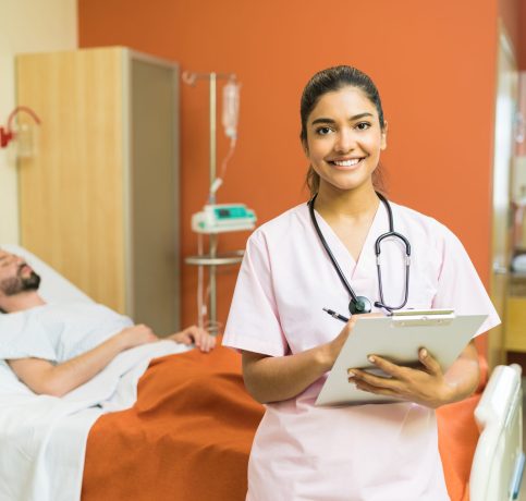 Confident female doctor with reports on clipboard standing against male patient at hospital