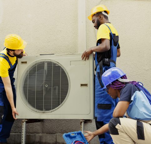 Knowleadgeable engineering team installing new outdoor air conditioner for home owner after replacing old condenser. Efficient technicians tasked with optimizing new HVAC system performance